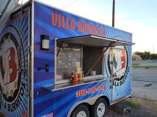 A colorful food truck named "Villa Burritos" with a menu displayed and condiments on the counter.