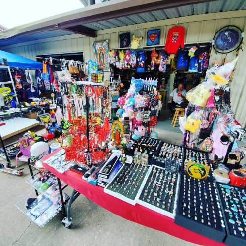 A vibrant market stall filled with colorful jewelry, toys, and various merchandise, with a person seated in the background.