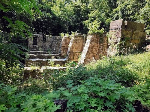 Ruins of an old stone structure surrounded by lush greenery and trees.