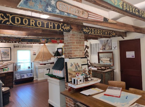 Interior of a museum featuring wooden signs, model boats, and various maritime displays.