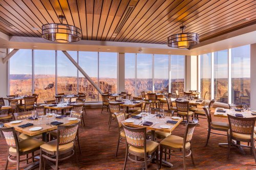 Elegant restaurant interior with wooden decor and large windows showcasing a stunning canyon view.