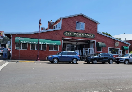 A red building with a sign reading "Old Town Mall" and "The Wheelhouse & Crownest," parked cars in front.