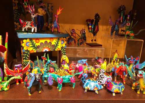 Colorful handcrafted wooden animals and figures displayed on a table, showcasing vibrant designs and intricate details.