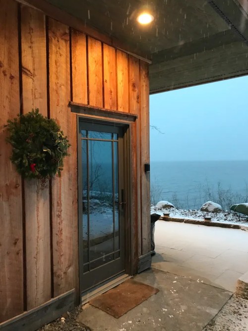 A wooden entrance with a wreath, overlooking a snowy lake scene in the background.