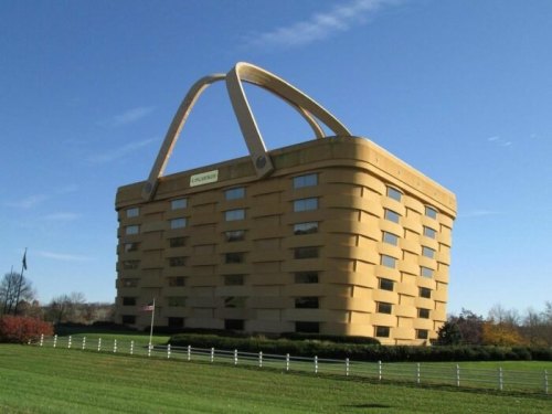 A large, basket-shaped building with a golden exterior and a prominent handle, set against a clear blue sky.