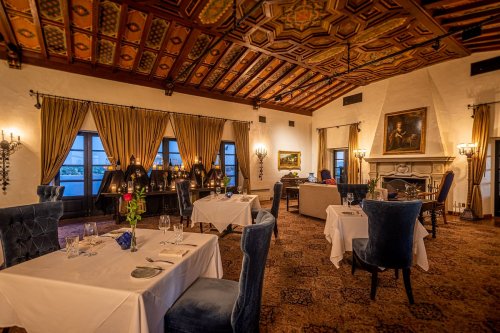 Elegant restaurant interior with ornate ceiling, plush seating, and candlelit tables set for dining.