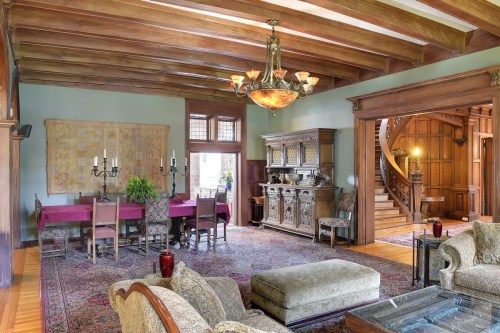 A spacious, elegantly furnished living room with wooden beams, a dining area, and ornate furniture.