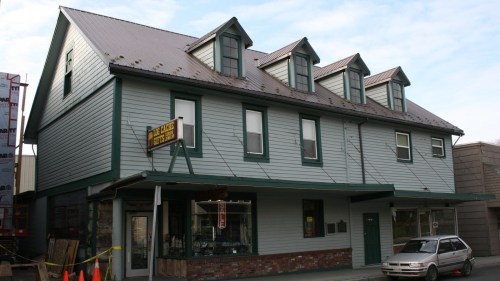 A three-story green building with a sloped roof and multiple windows, featuring a sign that reads "Orange Street."