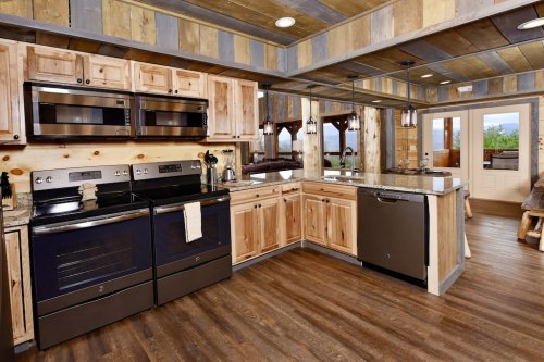 A modern kitchen with wooden cabinets, black appliances, and a spacious layout featuring a large window.