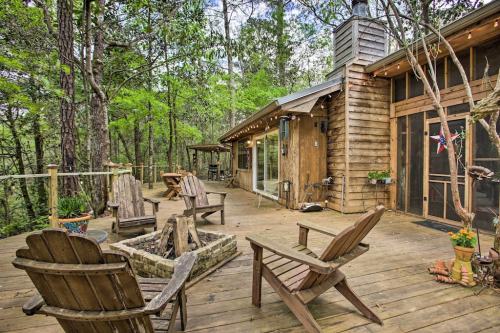 Cozy wooden cabin deck surrounded by trees, featuring a fire pit and Adirondack chairs for relaxation.