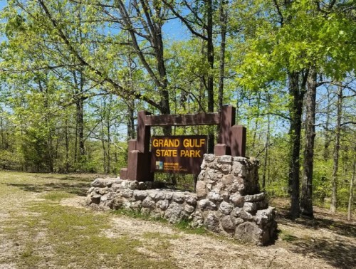 Sign for Grand Gulf State Park, surrounded by green trees and grass on a sunny day.
