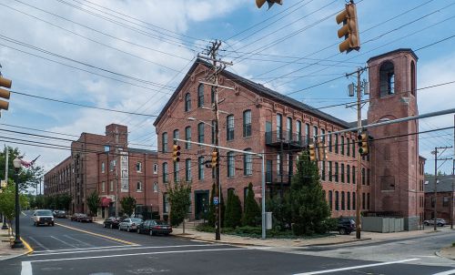 Historic brick buildings at an intersection, featuring a clock tower and traffic lights under a cloudy sky.