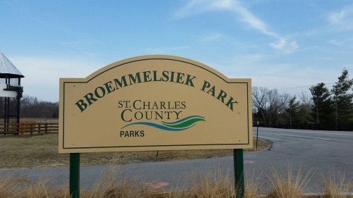 Sign for Broemmelsiek Park, St. Charles County Parks, with a clear sky and grassy area in the background.