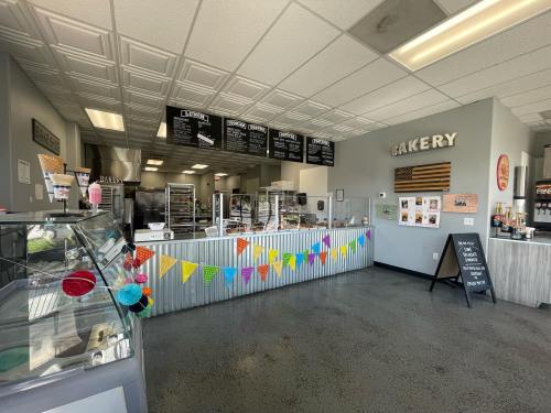 A bright bakery interior featuring a display case, colorful bunting, and a menu board on the wall.
