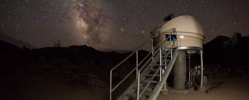 A dome-shaped observatory under a starry night sky, with the Milky Way visible in the background.
