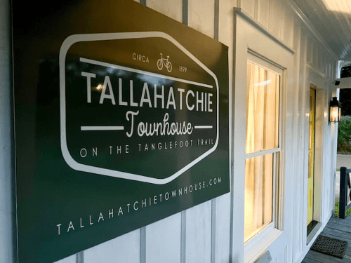 Sign for Tallahatchie Townhouse, featuring the tagline "On the Tanglefoot Trail," with a bicycle icon and website link.