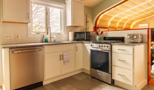 Bright kitchen featuring stainless steel appliances, a window, and modern cabinetry with a granite countertop.