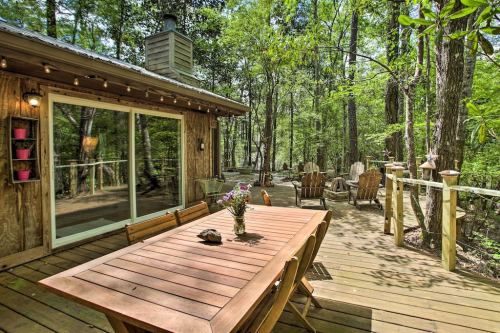 A wooden deck with a dining table and chairs, surrounded by lush green trees and a cozy outdoor seating area.