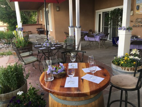 A charming outdoor dining area with tables set for guests, surrounded by flowers and greenery.