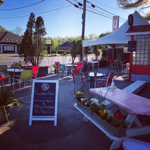 Outdoor dining area with colorful chairs, a chalkboard sign, and flower planters at a diner.