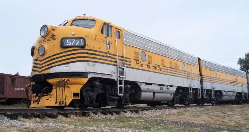 A vintage yellow and silver diesel locomotive labeled "Rio Grande" parked on a railway track.