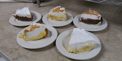 Five slices of pie on plates, featuring chocolate and lemon flavors, topped with whipped cream and crumbs.
