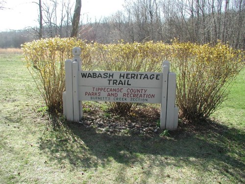 Sign for Wabash Heritage Trail in Tippecanoe County Parks and Recreation, surrounded by greenery.