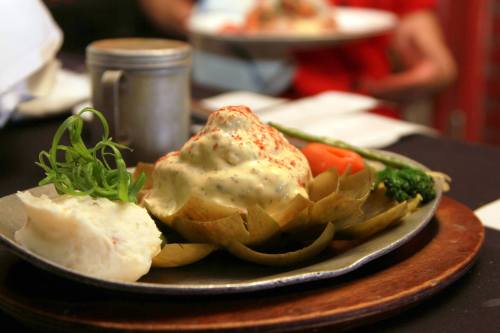 A plated dish featuring artichoke, creamy sauce, vegetables, and a side of mashed potatoes on a wooden serving board.
