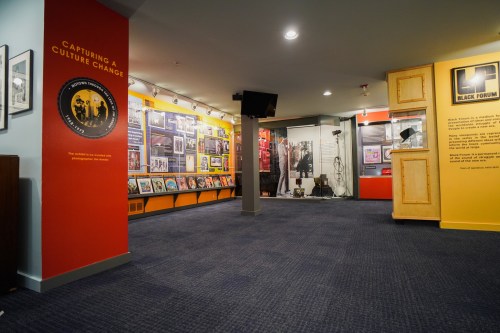 Exhibit space featuring walls of framed photos and memorabilia, highlighting cultural change and history.