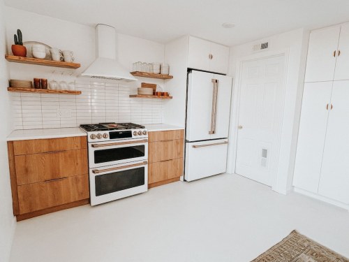 Modern kitchen featuring wooden cabinets, a white stove, and a sleek refrigerator against a bright, minimalist backdrop.
