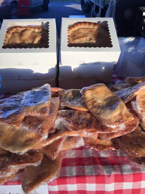 A display of wrapped pastries on a checkered tablecloth, with boxes of pastries in the background.