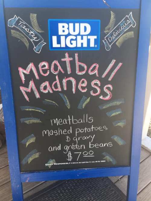 A chalkboard sign advertising "Meatball Madness" with meatballs, mashed potatoes, and green beans for $7.00.