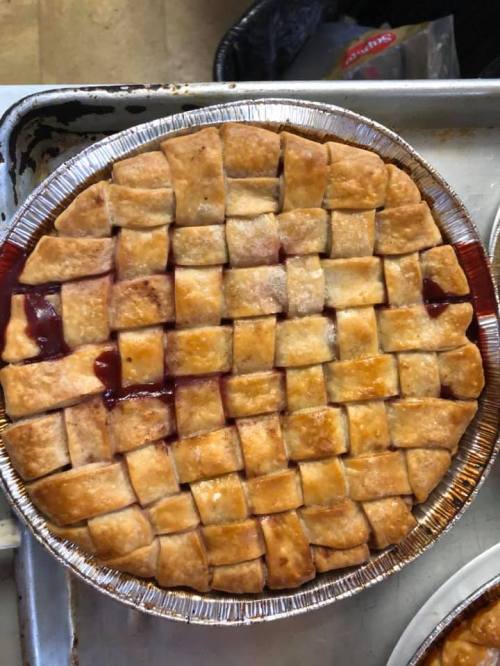 A freshly baked pie with a golden lattice crust, filled with a rich red fruit filling.