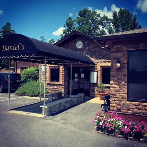 Exterior of Daniel's restaurant featuring a black awning, stone facade, and colorful flower beds.