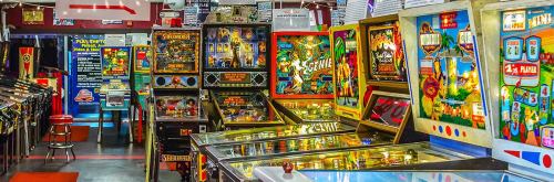 A vibrant arcade filled with vintage pinball machines and colorful game displays.