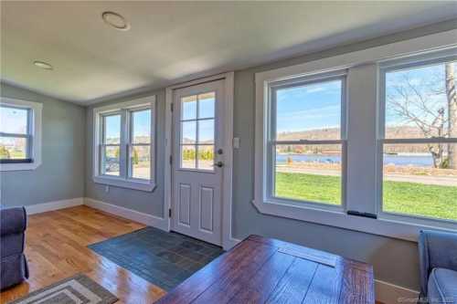 Bright interior view of a room with large windows overlooking a lake and greenery outside.