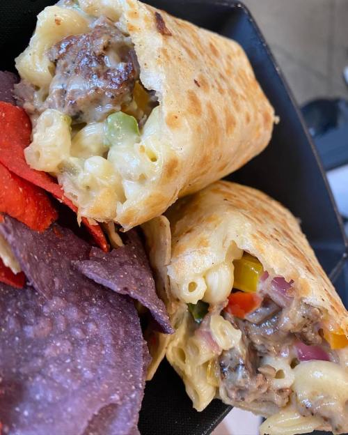 Two stuffed tortillas filled with macaroni, beef, and vegetables, served with colorful tortilla chips on the side.