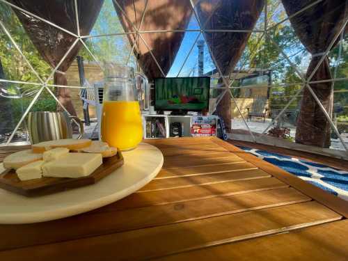 A cozy indoor scene featuring a plate of cheese, a pitcher of orange juice, and a TV in a geodesic dome.