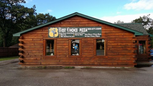 A wooden building with a sign for "Best Choice Pizza," featuring delivery info and hours of operation.