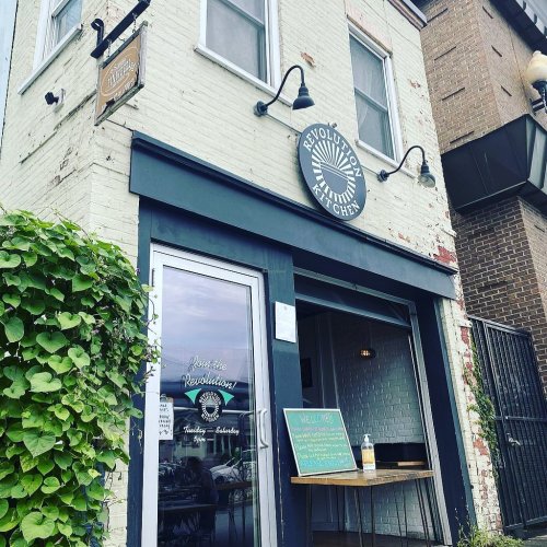 Exterior of a restaurant named "Revolution Chef," featuring a welcoming entrance and greenery nearby.