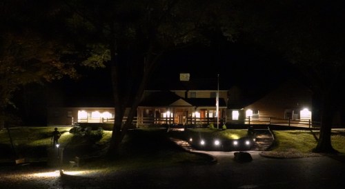 A dimly lit building at night, surrounded by trees and illuminated pathways, creating a serene atmosphere.