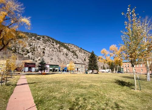 A scenic view of a small town with autumn trees, mountains in the background, and a clear blue sky.