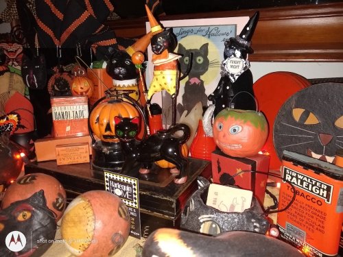 A colorful Halloween display featuring black cats, pumpkins, and various festive decorations on a table.