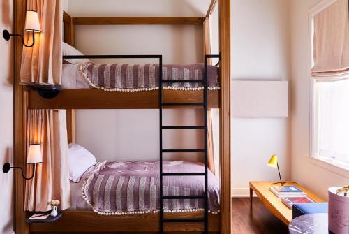 A cozy room featuring a wooden bunk bed with soft bedding, a small table, and warm lighting.