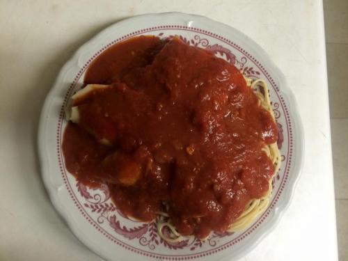 A plate of spaghetti topped with a rich red tomato sauce, served on a decorative white and red plate.