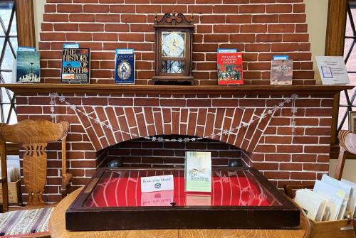 A brick fireplace with a clock and books displayed on the mantel, featuring a reading display in front.