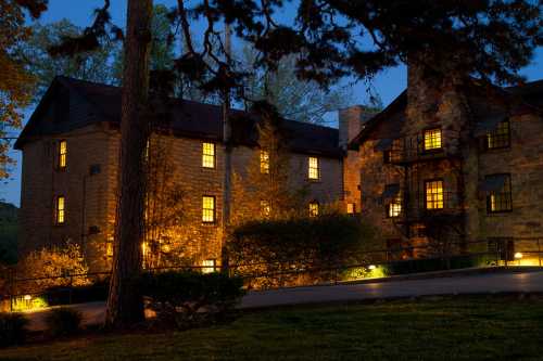 A stone building illuminated at night, surrounded by trees and soft landscape lighting.