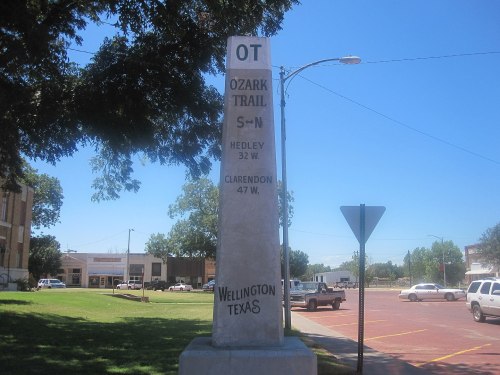 A stone marker for the Ozark Trail in Wellington, Texas, with directional distances to nearby towns.