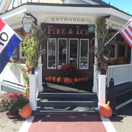 A charming entrance to a restaurant named "Fire & Ice," decorated with pumpkins and fall flowers.