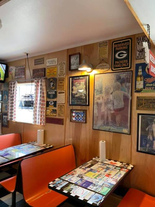 Cozy diner interior with orange booths, checkered floor, and walls adorned with vintage signs and memorabilia.